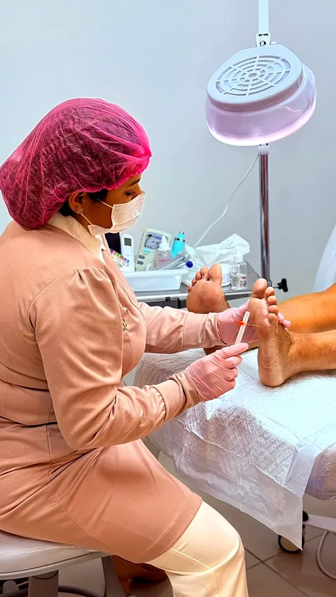 Dra. Daiana Lima, de touca e luvas, realizando avaliação na planta do pé de um paciente